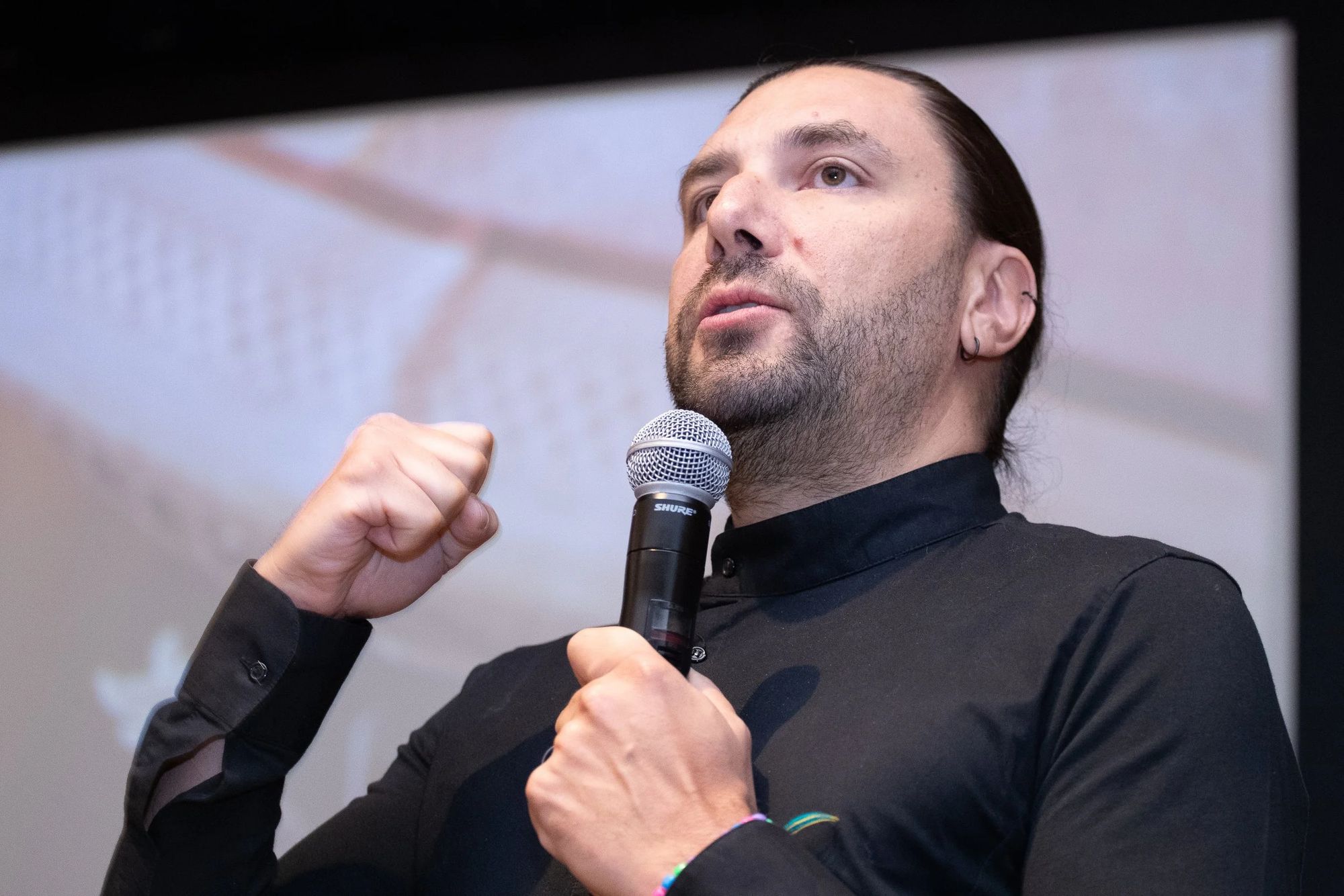 Lorenzo de Leo speaking on stage with a microphone